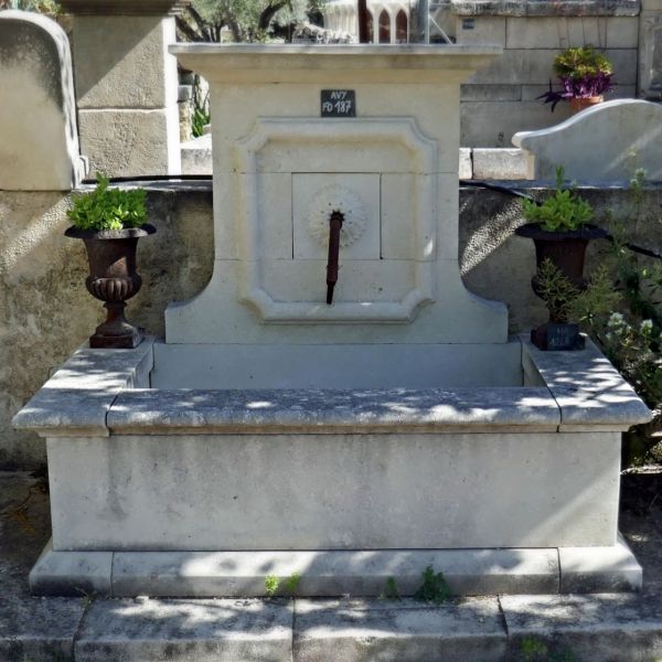 Fontaine de Provence en pierre naturelle avec fronton sculpté à la main et sortie d'eau en fer forgé.