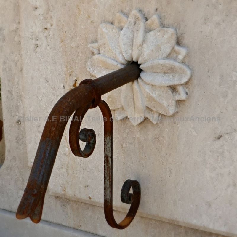 Wrought iron water outlet adorned with a beautiful hand carved rosette on the pediment of our decorative garden fountain | Atelier Alain BIDAL