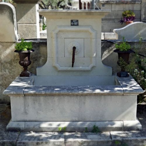 Fontaine de Provence en pierre naturelle avec fronton sculpté à la main et sortie d'eau en fer forgé.
